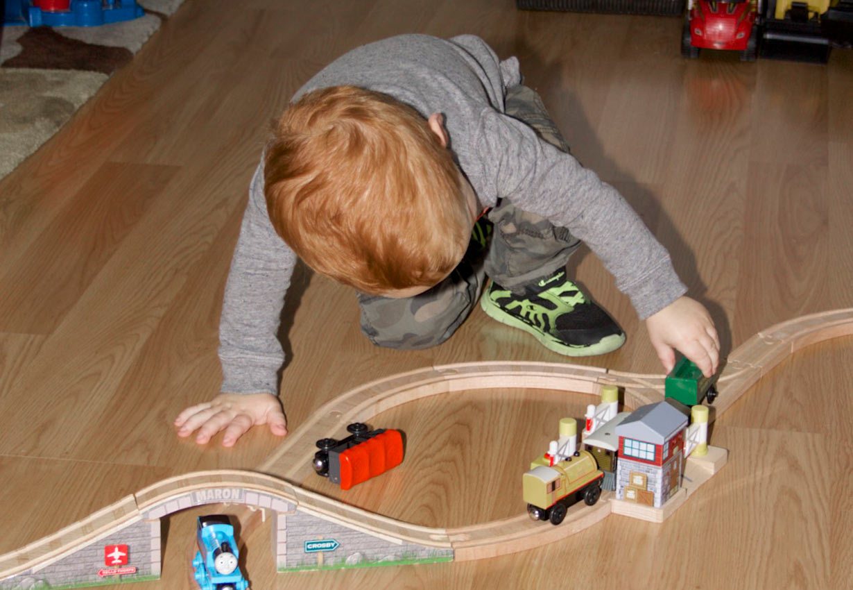 young child playing with a train set